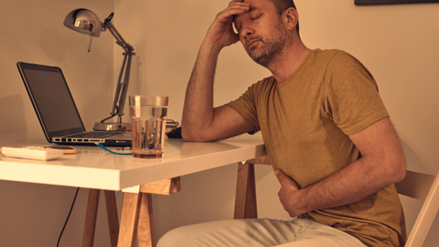 Man in chair experiencing colitis symptoms like discomfort and abdominal pain